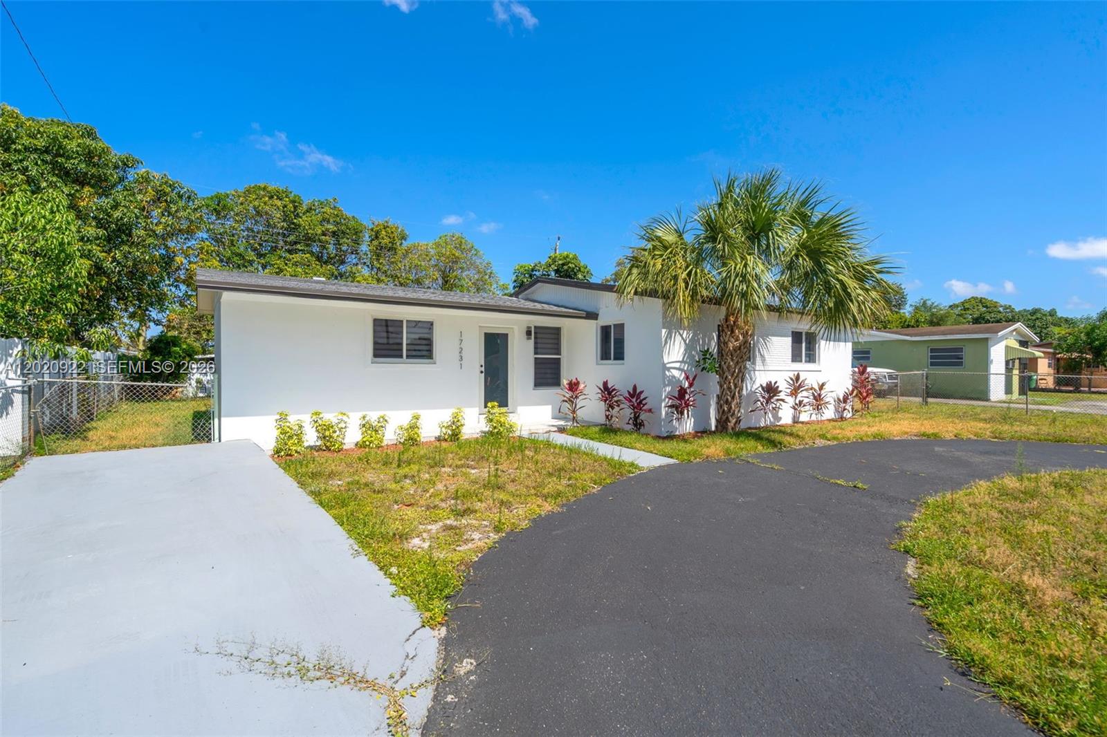 A white, single-story house features a palm tree, a paved driveway, and a front lawn — 17231 NW 24th Pl, Miami Gardens FL 33056, MIAMI GARDENS, FL