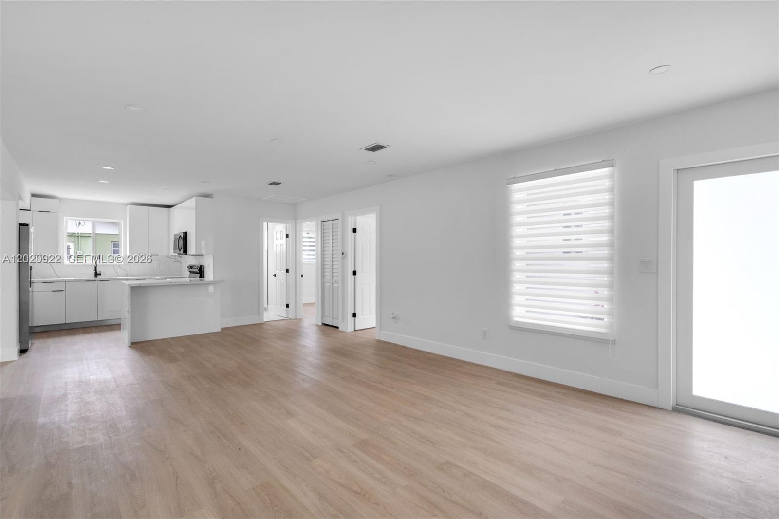 An open-concept kitchen and living area features white cabinetry, light wood flooring, and recessed lighting — 17231 NW 24th Pl, Miami Gardens FL 33056, MIAMI GARDENS, FL