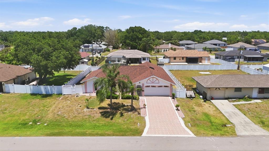 An aerial view shows a single-story house with a paved driveway and a fenced yard — 21452 BANCROFT AVENUE, PORT CHARLOTTE, FL