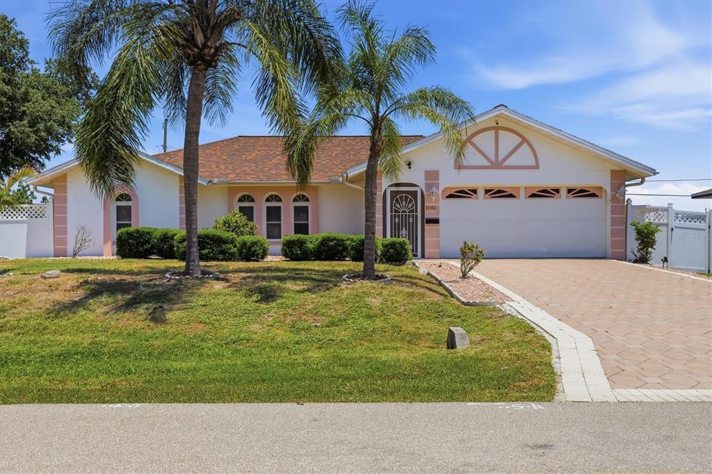 A single-story house with a paved driveway, palm trees, and a two-car garage — 21452 BANCROFT AVENUE, PORT CHARLOTTE, FL