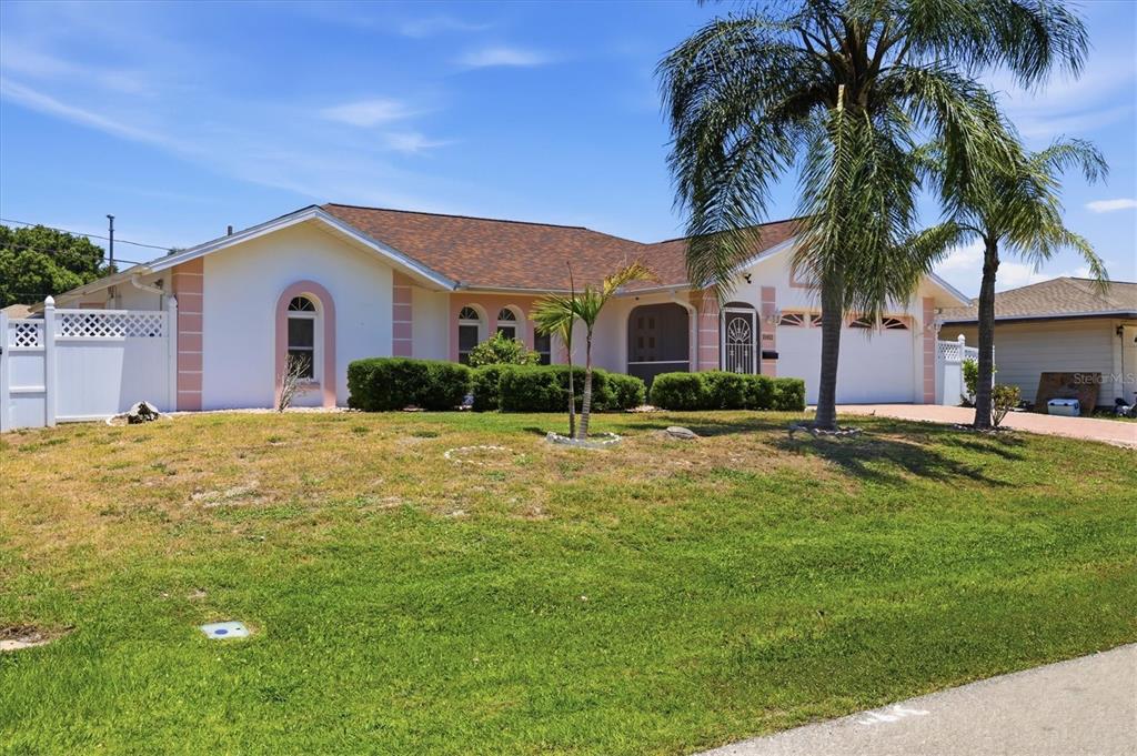 A single-story house with a white exterior, a brown roof, and a palm tree — 21452 BANCROFT AVENUE, PORT CHARLOTTE, FL