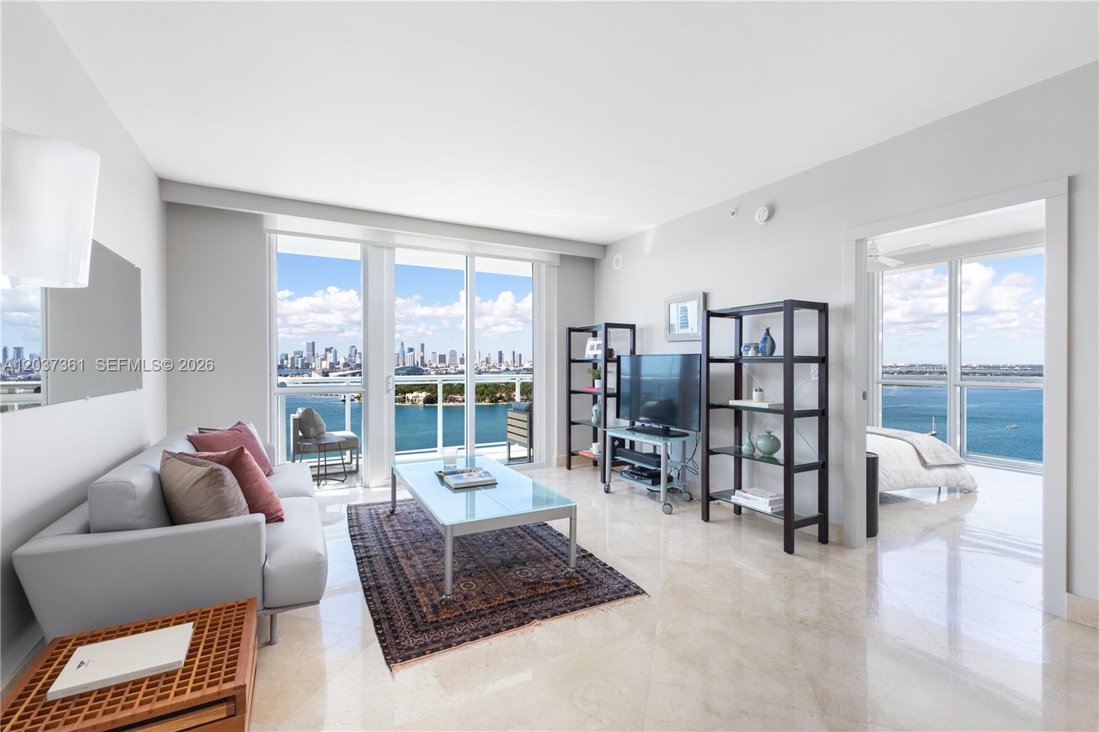 A living room with a glass coffee table, sofa, and floor-to-ceiling windows overlooking the ocean — 520 West Ave # 2004, Miami Beach FL 33139, MIAMI BEACH, FL