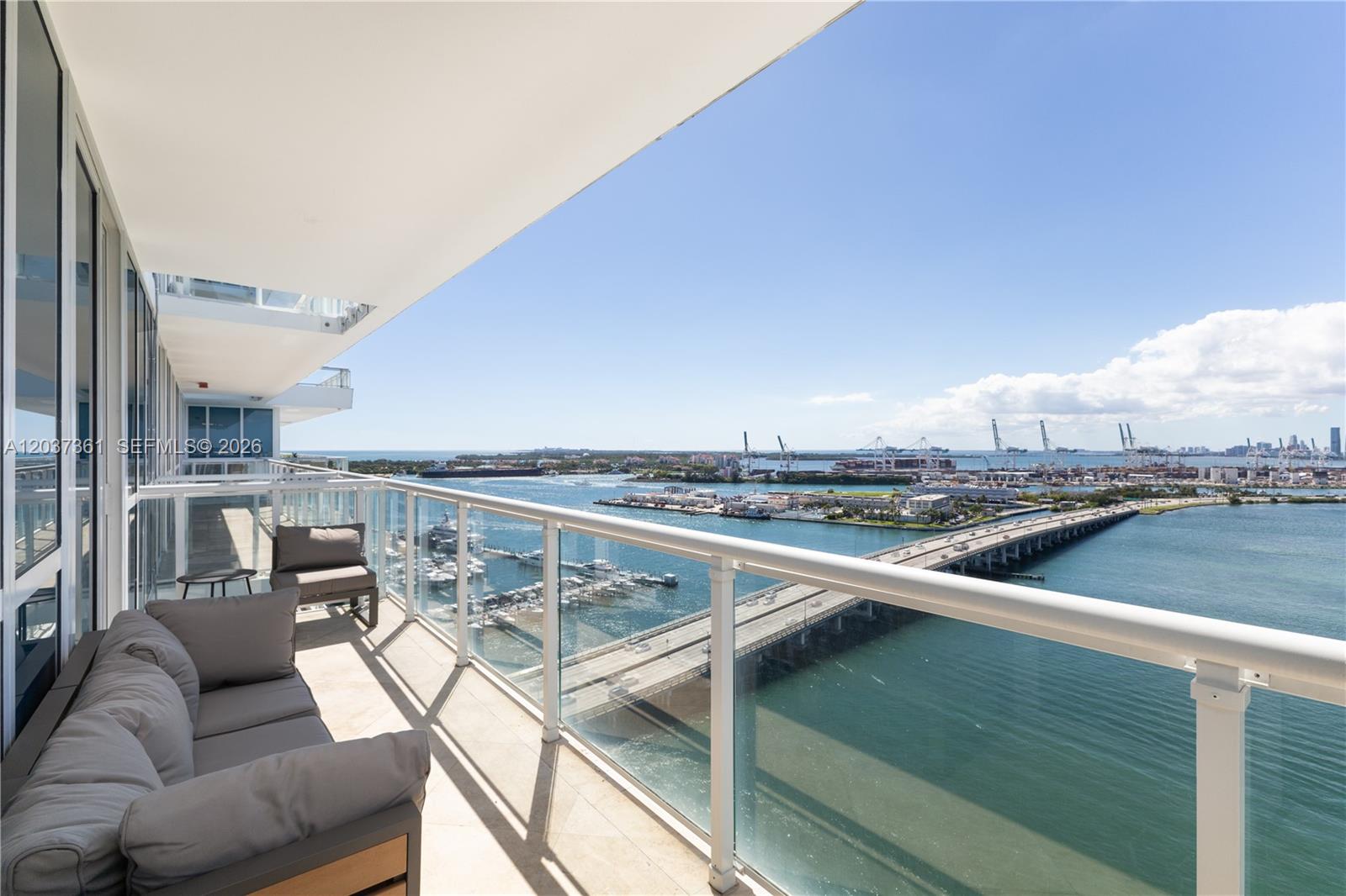 A balcony with outdoor seating overlooks a bridge, a marina, and a harbor — 520 West Ave # 2004, Miami Beach FL 33139, MIAMI BEACH, FL