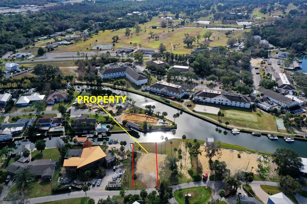 An aerial view shows a vacant waterfront lot marked with lines near a residential area — 1845 SE 3RD COURT, CRYSTAL RIVER, FL