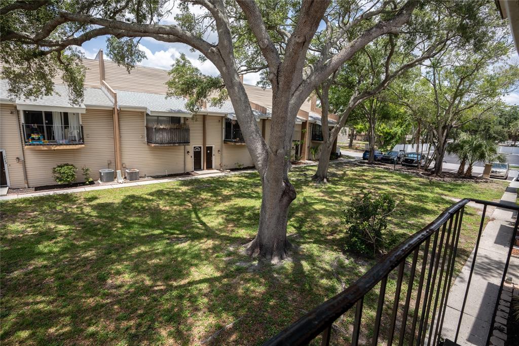 A view from a balcony overlooking a grassy courtyard with large trees and townhouses — 5409 SWEETWATER TERRACE CIRCLE, TAMPA, FL