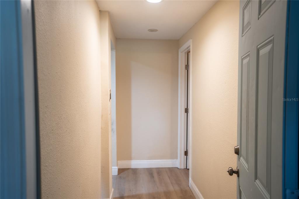 A hallway with light-colored walls, wood-look flooring, and a door on the right — 5409 SWEETWATER TERRACE CIRCLE, TAMPA, FL