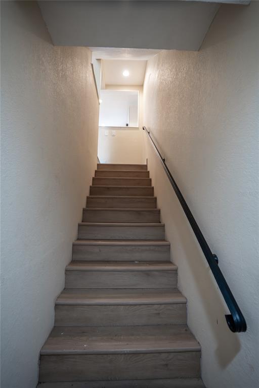 A straight staircase with light wood-look steps and a black metal handrail leads upward — 5409 SWEETWATER TERRACE CIRCLE, TAMPA, FL