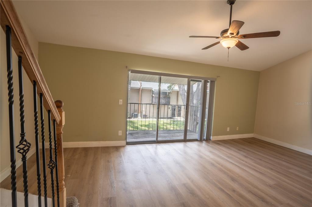 A living room features light wood-look flooring, a ceiling fan, and sliding glass patio doors — 5409 SWEETWATER TERRACE CIRCLE, TAMPA, FL