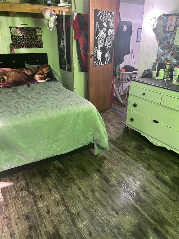 A bedroom features a bed with a patterned comforter, a light green dresser, and wood-look flooring — 6359 VASSAR DRIVE, KEYSTONE HEIGHTS, FL