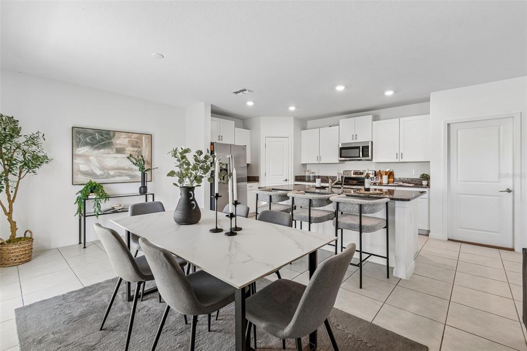 A dining area with a marble-topped table sits adjacent to a kitchen with white cabinets — 9920 SPANISH LIME COURT, RIVERVIEW, FL