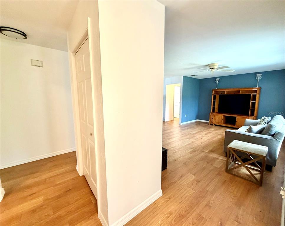 A living room with wood-look flooring, a blue accent wall, and a wooden entertainment center — 9972 SW 151ST PLACE, LAKE BUTLER, FL