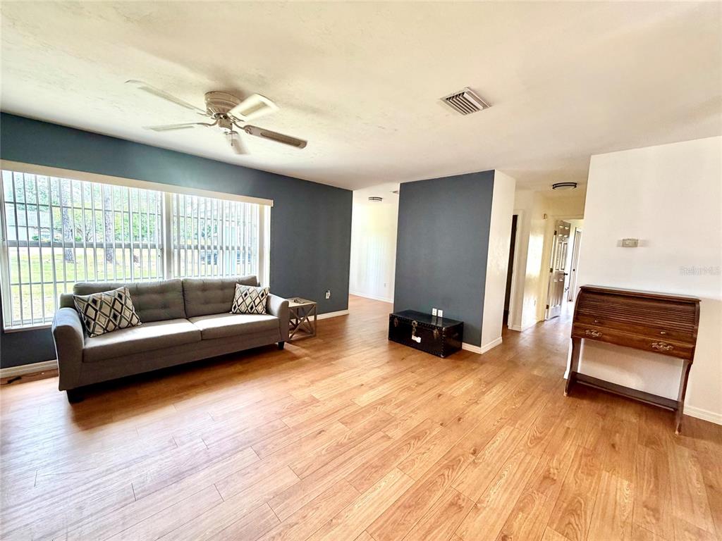 A living room features wood-look flooring, a gray sofa, and a dark accent wall — 9972 SW 151ST PLACE, LAKE BUTLER, FL