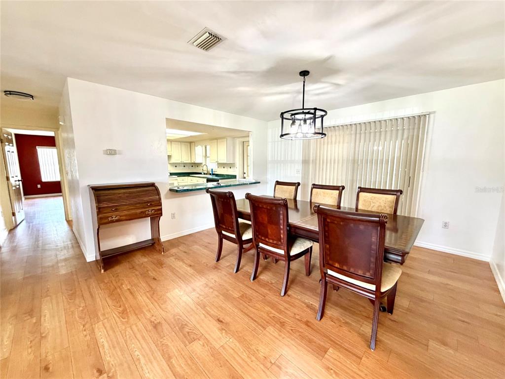A dining room with wood-look flooring, a dark wood table and chairs, and a kitchen pass-through — 9972 SW 151ST PLACE, LAKE BUTLER, FL