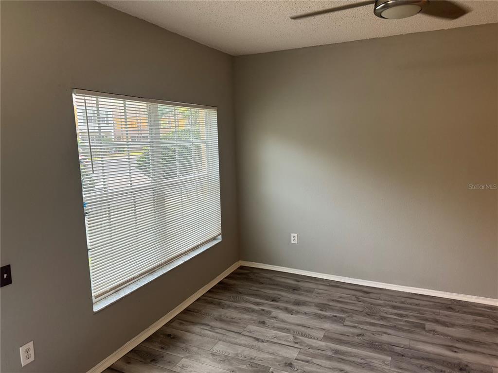 An empty room features gray walls, wood-look laminate flooring, and a window with white blinds — 30059 GRANDA HILLS COURT, WESLEY CHAPEL, FL