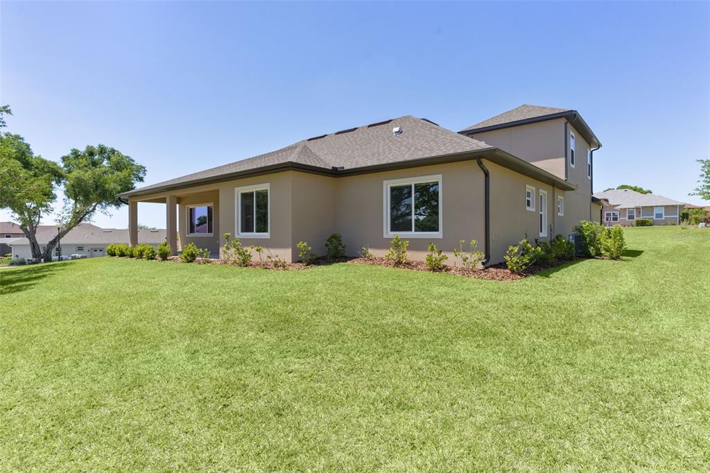 The exterior of a tan, two-story house with a brown shingled roof and green lawn — 39654 GROVE HEIGHTS, LADY LAKE, FL