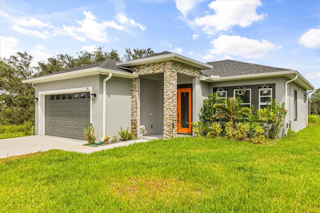 A single-story house with a gray exterior, stone-accented entryway, and a bright orange front door — 423 VERNON COURT, KISSIMMEE, FL