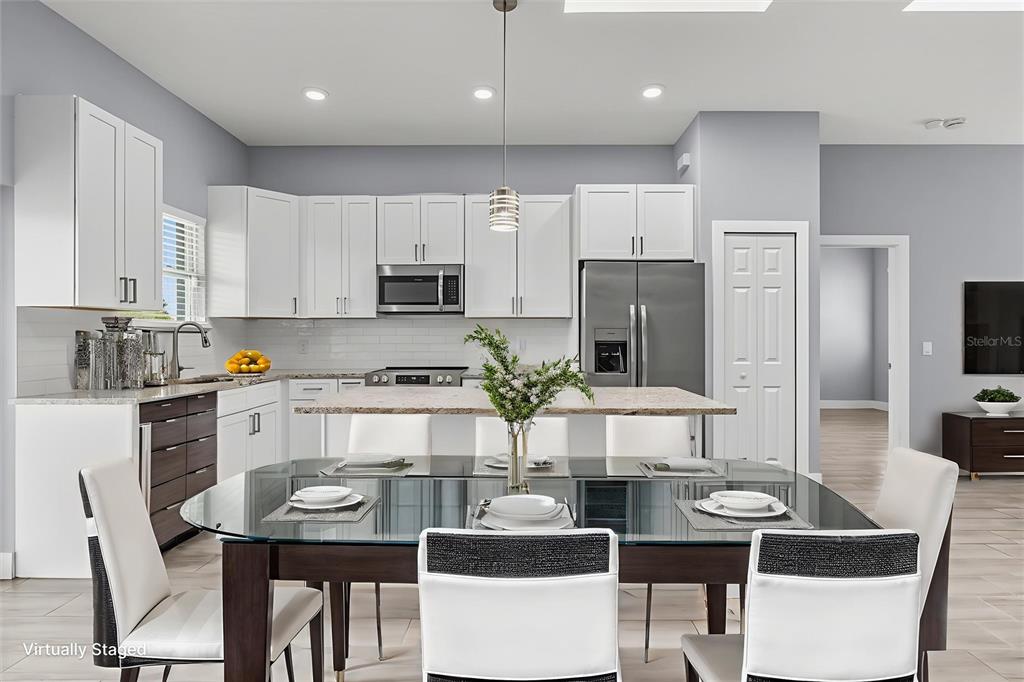 A modern kitchen features white cabinets, stainless steel appliances, and a glass-topped dining table — 423 VERNON COURT, KISSIMMEE, FL