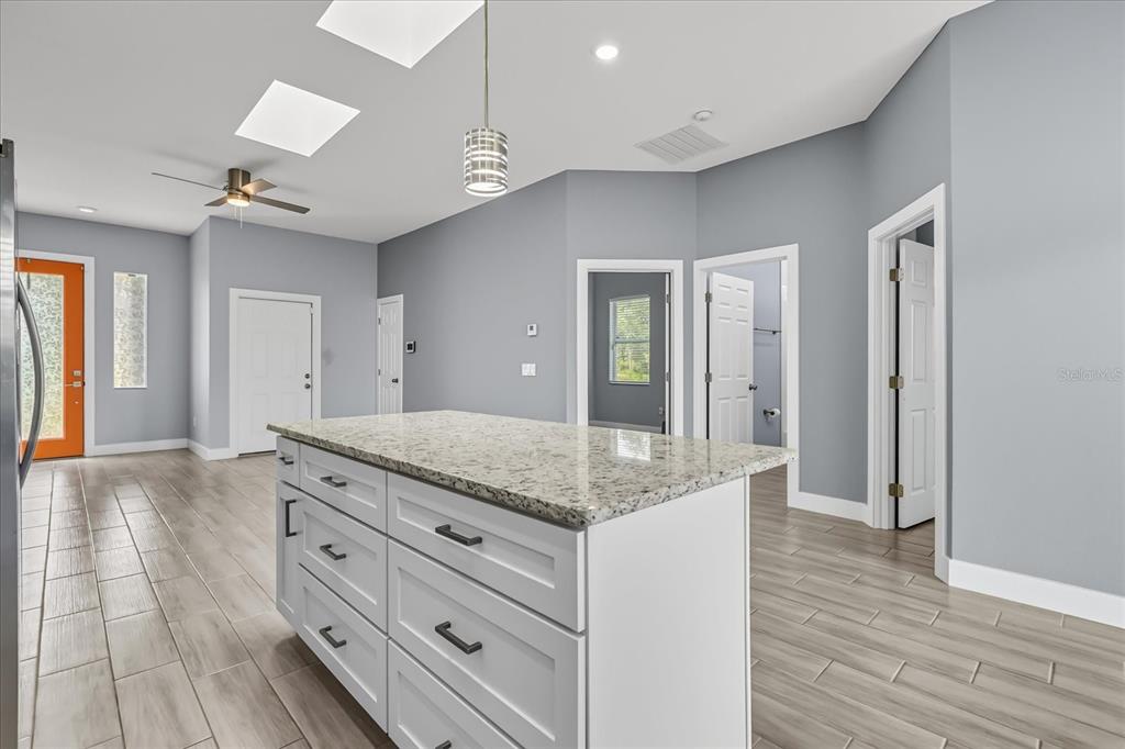 A kitchen island with a granite countertop sits in a room with gray walls — 423 VERNON COURT, KISSIMMEE, FL