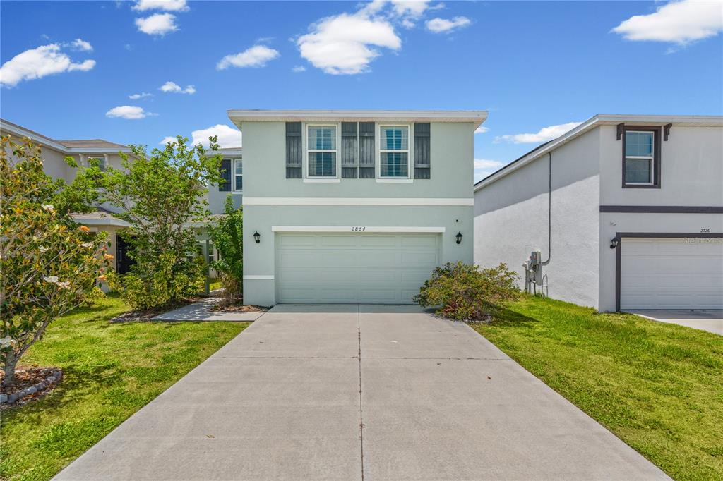 A two-story house with a light green exterior, a two-car garage, and a concrete driveway — 2804 ROCK SOUND STREET, BRADENTON, FL