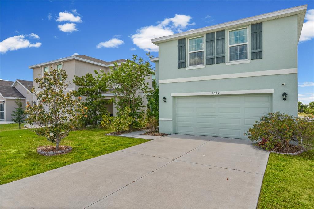 A two-story light green house with a two-car garage and a concrete driveway — 2804 ROCK SOUND STREET, BRADENTON, FL