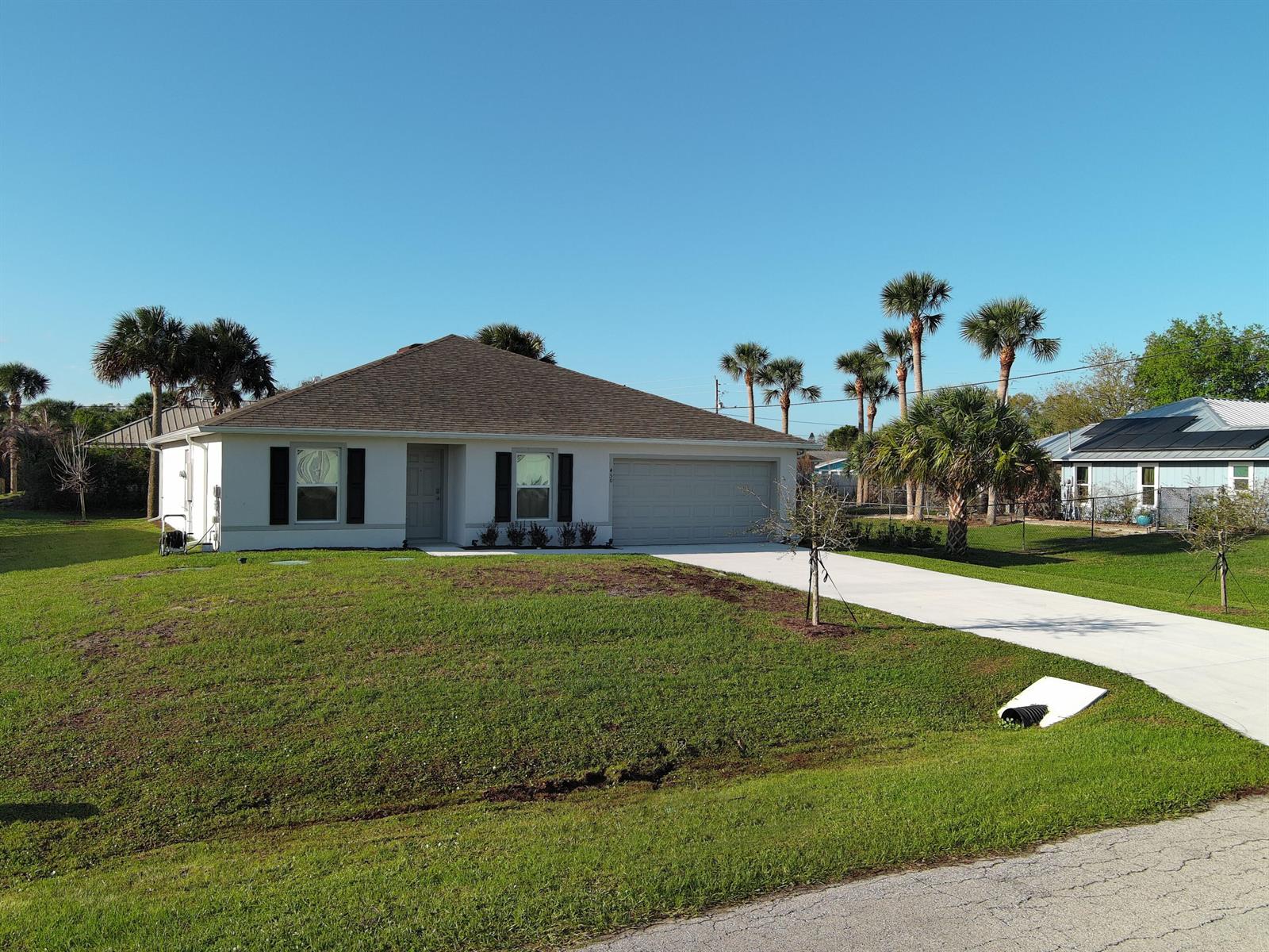A single-story white house with a gray roof and a concrete driveway sits on grass — 450 Kendall Avenue, Sebastian FL 32958, SEBASTIAN, FL