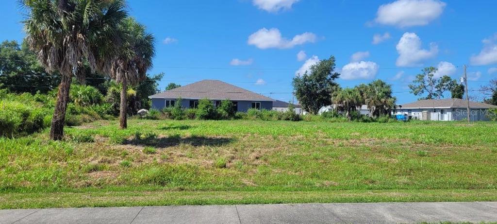 A vacant, grassy residential lot with palm trees and neighboring houses in the background — 4435 S ACCESS ROAD, ENGLEWOOD, FL