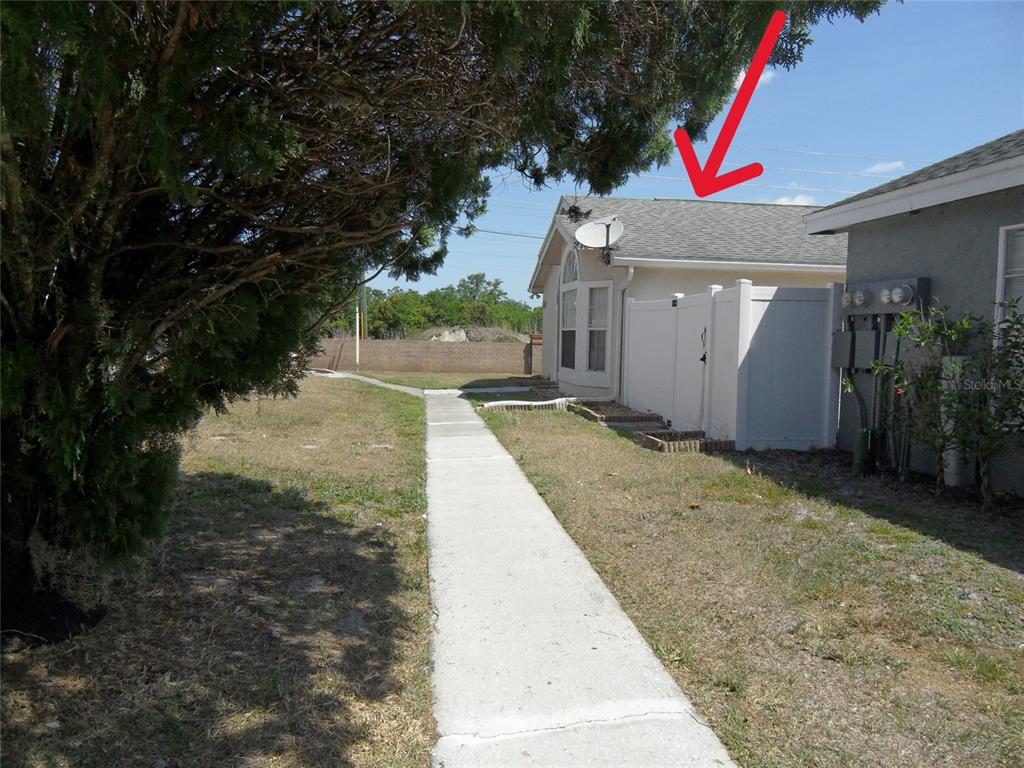 A sidewalk leads past a white fence toward the side of a house with a roof — 276 SAN GABRIEL STREET, WINTER SPRINGS, FL