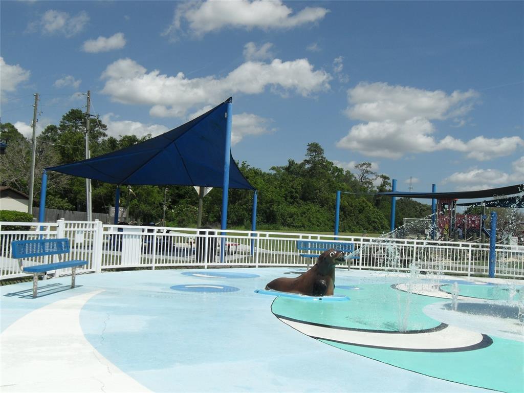 A splash pad area features a sea lion water feature, blue benches, and shade sails — 276 SAN GABRIEL STREET, WINTER SPRINGS, FL