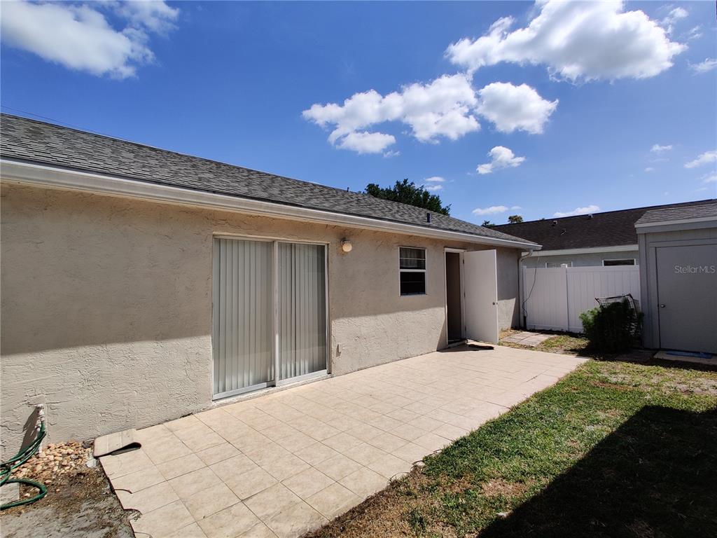 A beige stucco house exterior features a tiled patio, sliding glass doors, and an open door — 276 SAN GABRIEL STREET, WINTER SPRINGS, FL