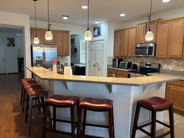 A kitchen features wooden cabinets, granite countertops, a breakfast bar, and four bar stools — 9819 ROYAL VISTA AVENUE, CLERMONT, FL