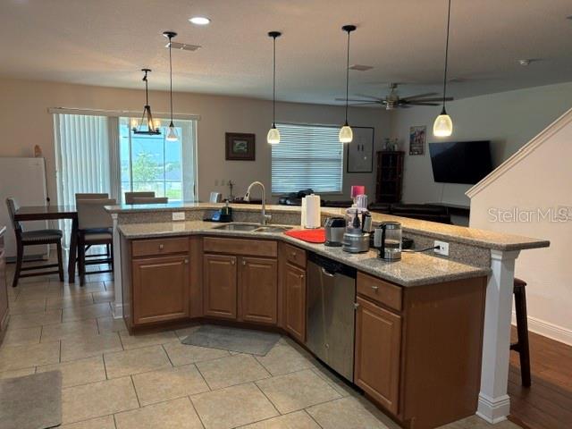 A kitchen with wood cabinets, granite countertops, and pendant lighting overlooks a dining area — 9819 ROYAL VISTA AVENUE, CLERMONT, FL