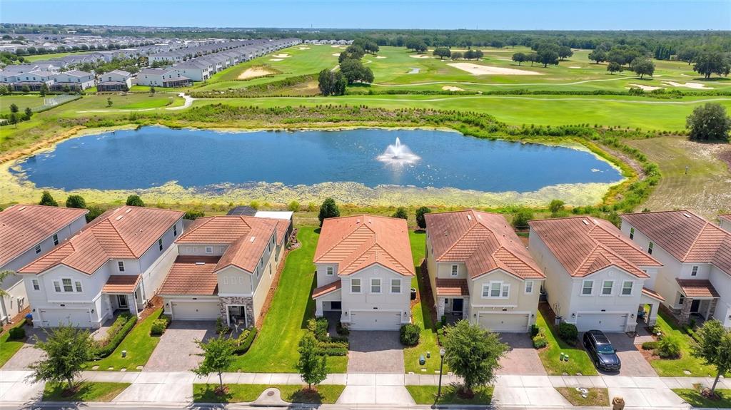 An aerial view shows a row of suburban houses facing a pond with a fountain — 8801 BETH PAGE LANE, DAVENPORT, FL