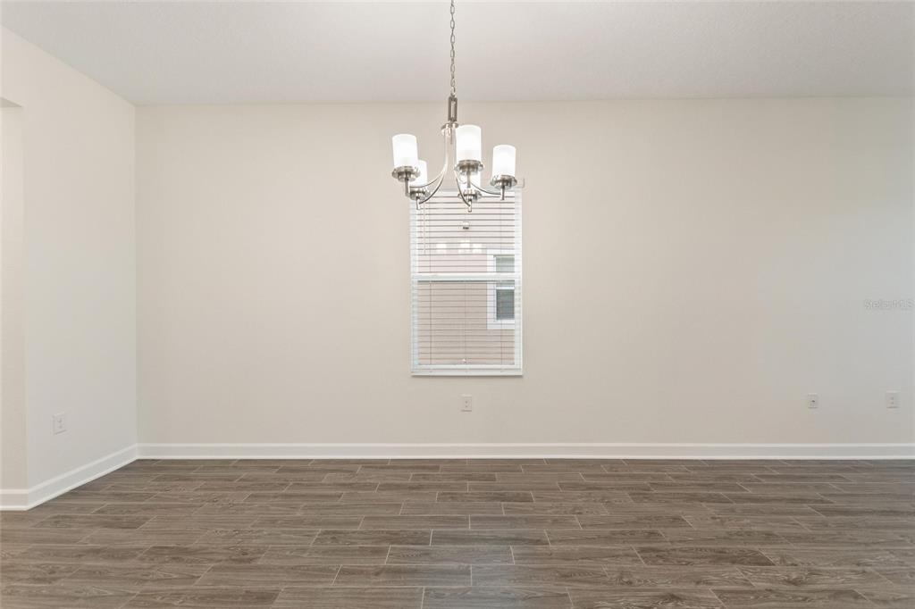A dining room features light-colored walls, a central chandelier, and wood-look tile flooring — 8801 BETH PAGE LANE, DAVENPORT, FL