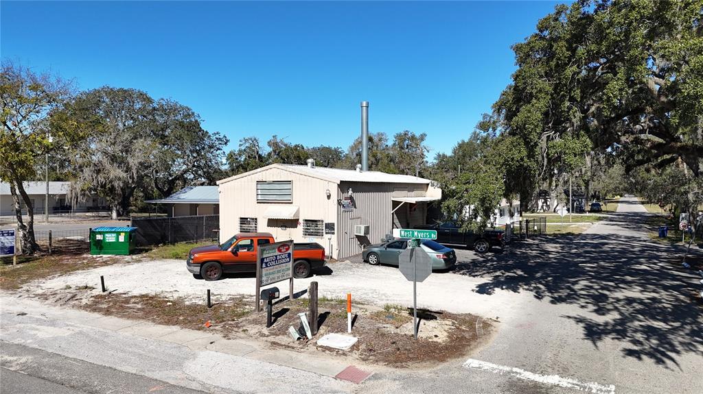 An exterior view of a metal-sided auto body shop with a gravel parking lot — 10 BARRY AVENUE, MASCOTTE, FL