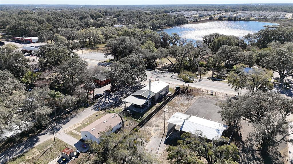 An aerial view shows several small buildings, a parking area, and a lake surrounded by trees — 10 BARRY AVENUE, MASCOTTE, FL