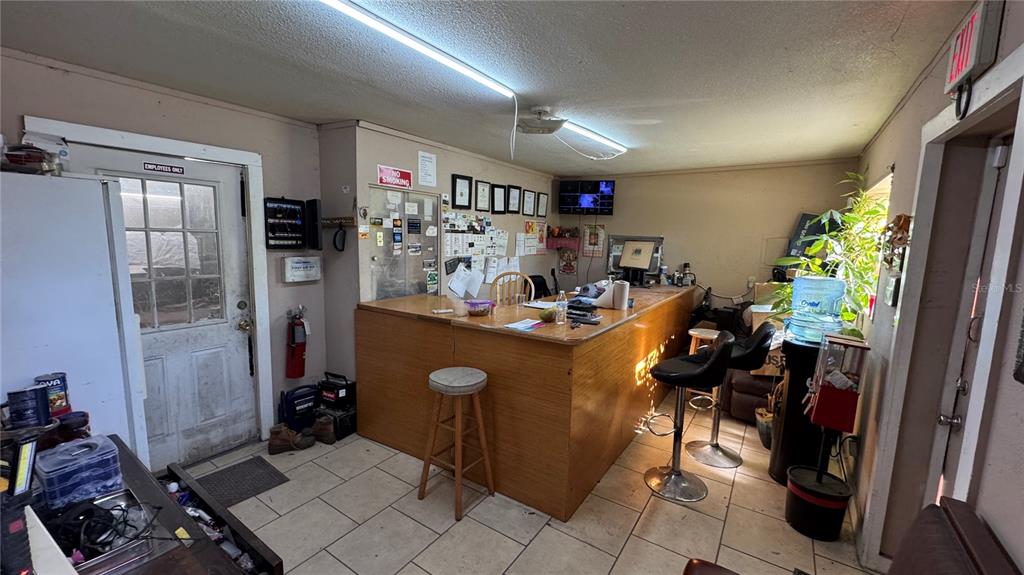 A commercial office space features a wooden service counter, tiled floors, and a glass-paneled door — 10 BARRY AVENUE, MASCOTTE, FL