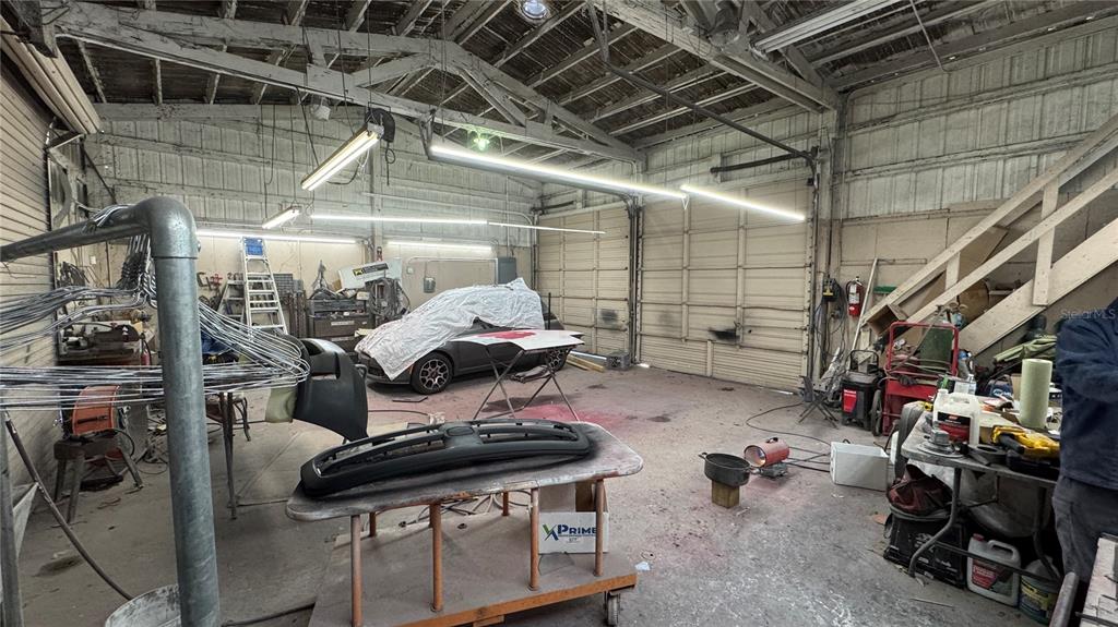 An industrial auto repair garage features a concrete floor, exposed rafters, and a covered car — 10 BARRY AVENUE, MASCOTTE, FL