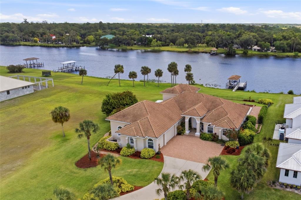 A swimming pool with a fountain sits on a stone patio overlooking a river — 2504 CALOOSA SHORES DRIVE, LABELLE, FL