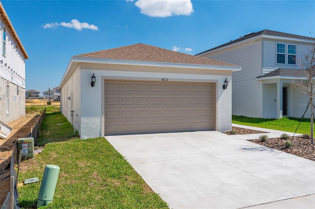 A beige, single-story garage with a concrete driveway sits between two residential houses — 3633 CAMBRIDGE BROOK DRIVE, DAVENPORT, FL