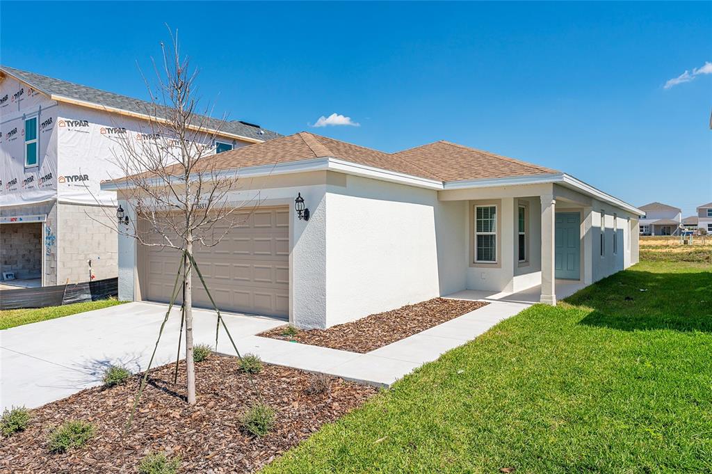 A single-story house with a beige garage, white stucco walls, and a light blue door — 3633 CAMBRIDGE BROOK DRIVE, DAVENPORT, FL