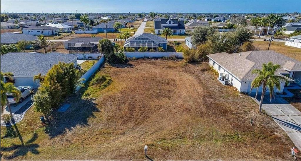 An aerial view of a vacant residential lot situated between two single-family homes — 1730 NW JUANITA PLACE, CAPE CORAL, FL