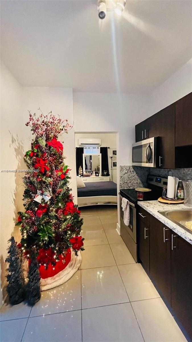 A kitchen with dark cabinets and granite countertops features a decorated Christmas tree nearby — 876 SW 2nd St, Miami FL 33130, MIAMI, FL