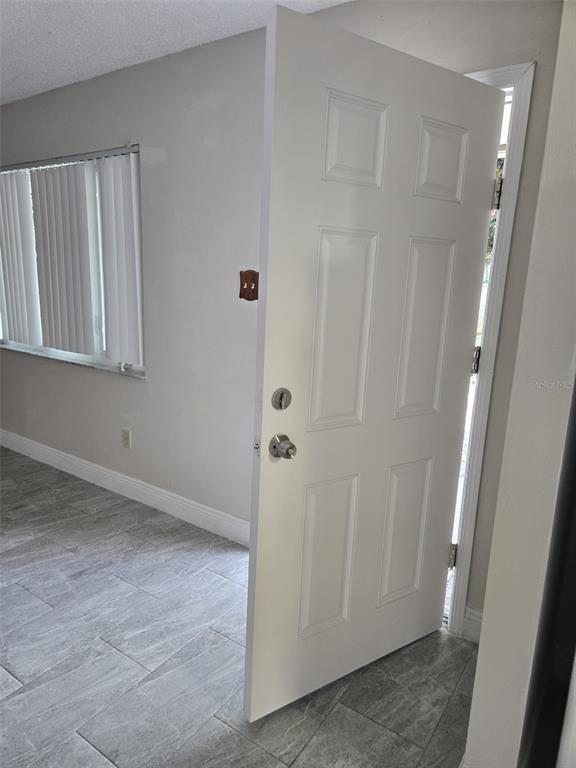 An open white six-panel door leads into a room with light gray tile flooring — 1420 SIMMONS ROAD, KISSIMMEE, FL
