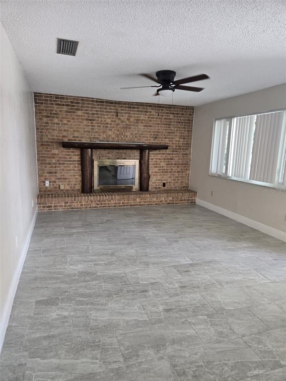 A living room features a brick fireplace with a log mantel and gray tile flooring — 1420 SIMMONS ROAD, KISSIMMEE, FL
