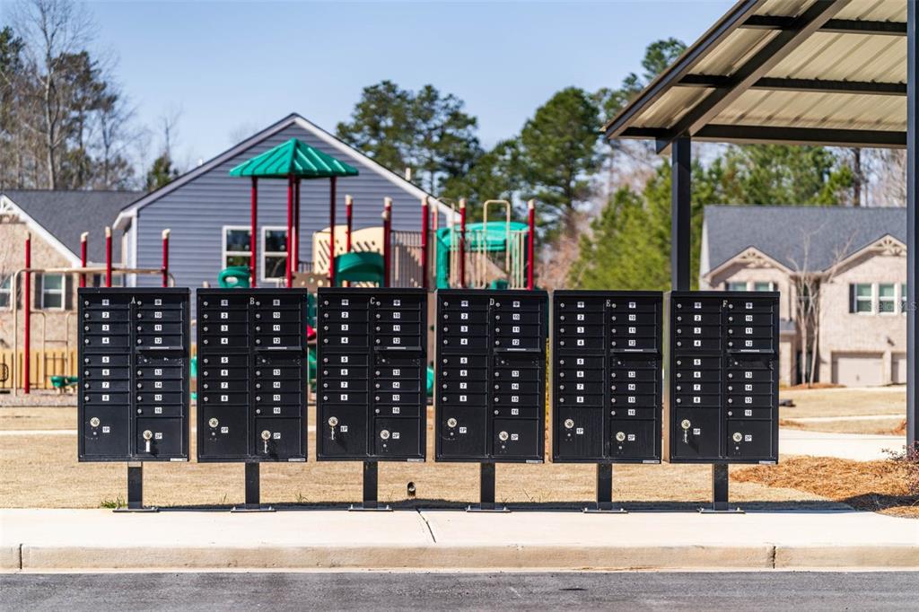 A row of black metal cluster mailboxes stands outdoors in front of a playground — 7304 TOLAR ROAD, FAIRBURN, GA