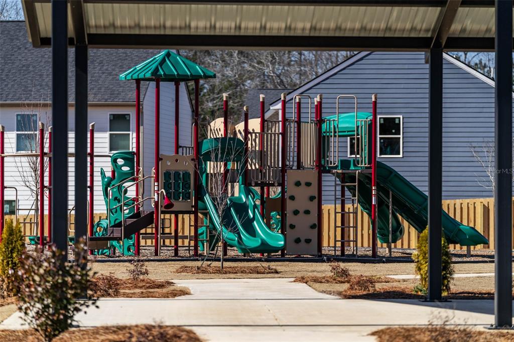 A colorful playground with slides and climbing structures sits outdoors in a residential neighborhood — 7304 TOLAR ROAD, FAIRBURN, GA