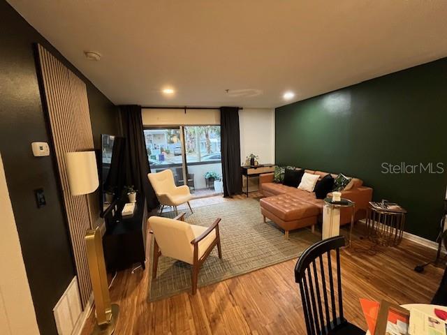 A living room features a dark green accent wall, wood flooring, and a sliding glass door — 406 S CEDAR AVENUE UNIT 107, TAMPA, FL