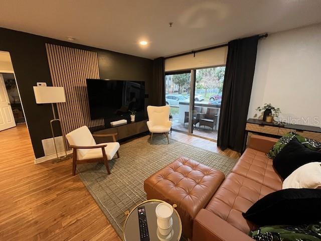 A living room features a wood-slat accent wall, a large television, and a leather sofa — 406 S CEDAR AVENUE UNIT 107, TAMPA, FL