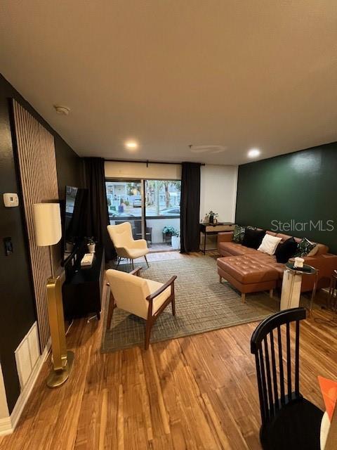 A living room features wood flooring, a leather sectional, two armchairs, and a dark accent wall — 406 S CEDAR AVENUE UNIT 107, TAMPA, FL
