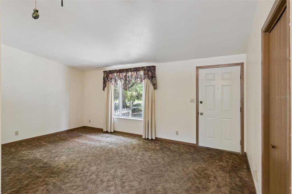 An empty room features brown carpeting, white walls, a window with a valance, and a door — 3803 YOUNG ROAD, LAKE WALES, FL